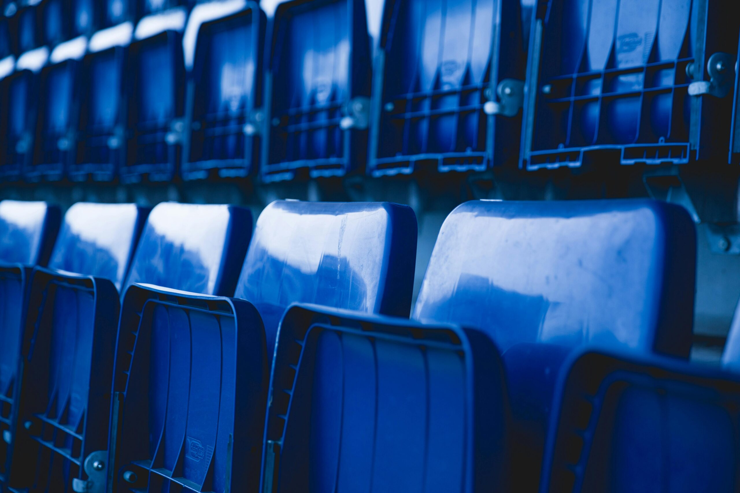 Close-up of empty blue stadium seats arranged in a repetitive pattern.